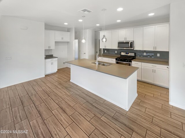 kitchen featuring stainless steel appliances, a sink, visible vents, white cabinets, and wood tiled floor