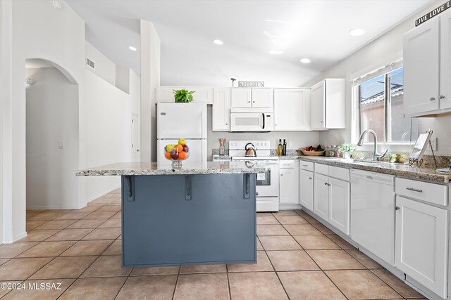 kitchen with white appliances, light stone counters, a center island, and white cabinetry