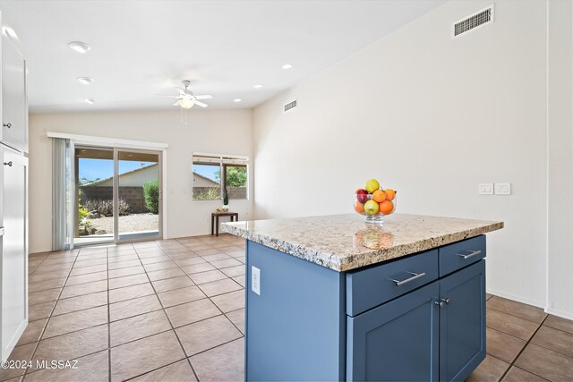 kitchen featuring a center island, lofted ceiling, light tile patterned flooring, ceiling fan, and blue cabinets