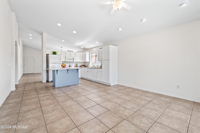 kitchen with vaulted ceiling, white appliances, a center island, ceiling fan, and white cabinets