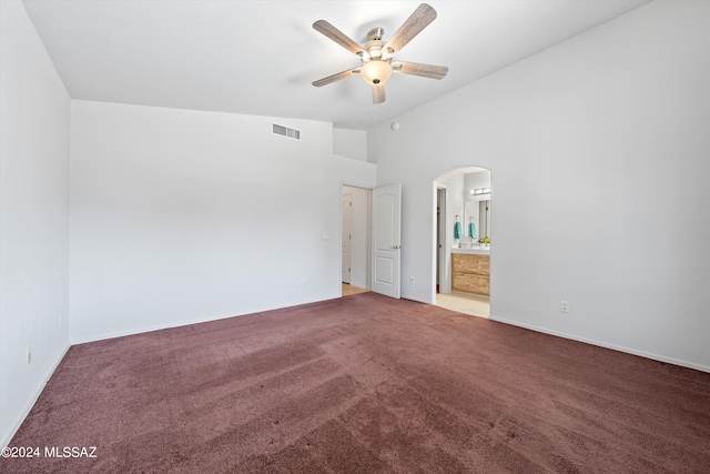 unfurnished bedroom featuring carpet flooring, ceiling fan, ensuite bath, and vaulted ceiling