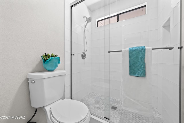 bathroom with toilet and a shower with shower door