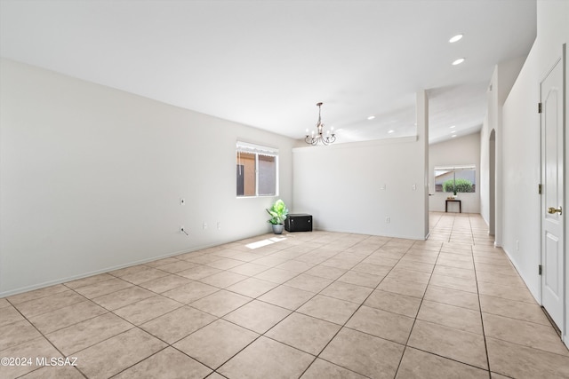 tiled empty room with lofted ceiling and a chandelier