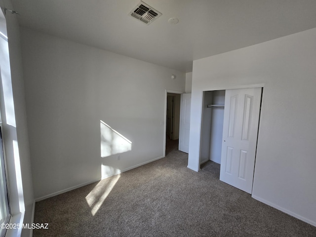 unfurnished bedroom with a closet and dark colored carpet