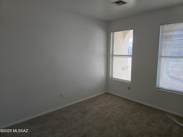 empty room with a healthy amount of sunlight and dark colored carpet