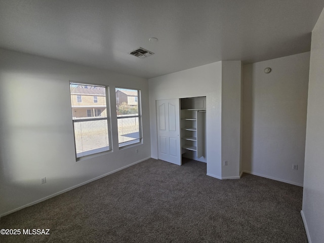 unfurnished bedroom featuring dark carpet and a closet