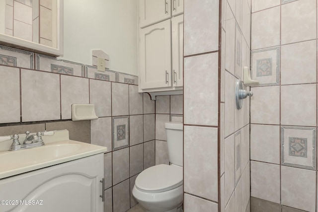 bathroom featuring vanity, tile walls, and toilet