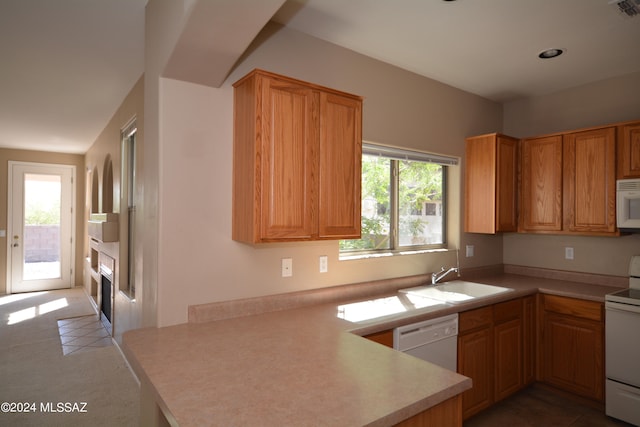 kitchen with white appliances, kitchen peninsula, sink, and tile patterned flooring
