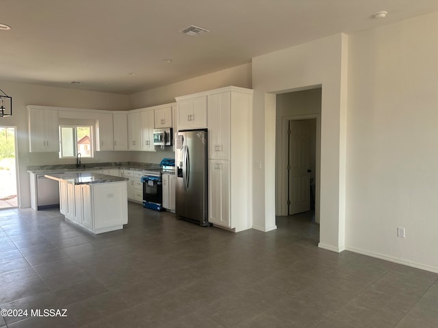 kitchen with a center island, stainless steel appliances, light stone counters, and white cabinets