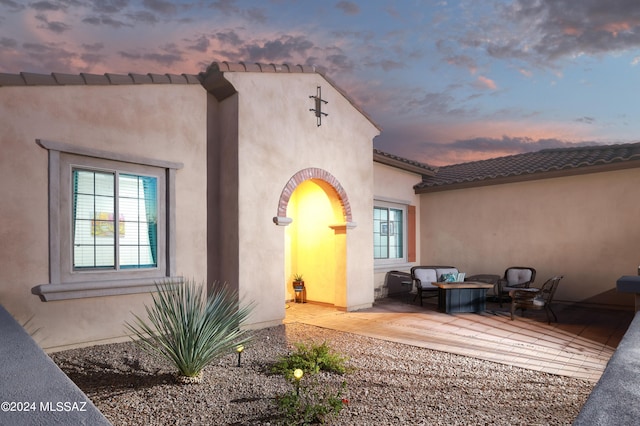 property entrance with stucco siding, a tile roof, and a patio