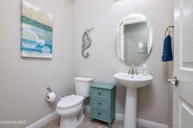 bathroom featuring tile patterned flooring, toilet, baseboards, and a sink