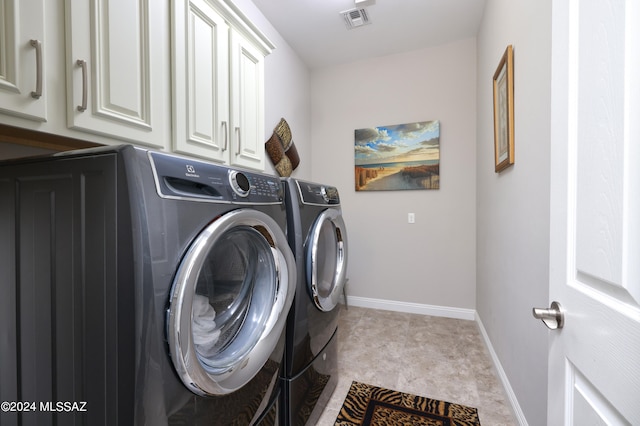 clothes washing area featuring cabinets and washing machine and clothes dryer