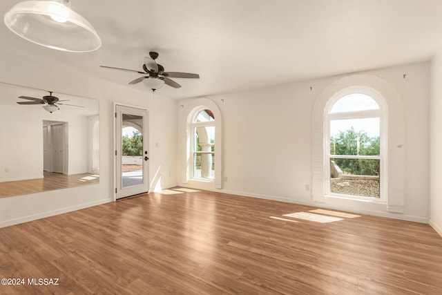 unfurnished room with a ceiling fan, baseboards, and wood finished floors