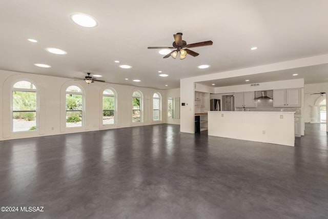 unfurnished living room with a healthy amount of sunlight, ceiling fan, finished concrete floors, and recessed lighting