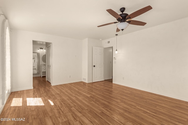 unfurnished bedroom with ensuite bathroom, ceiling fan, wood finished floors, visible vents, and baseboards