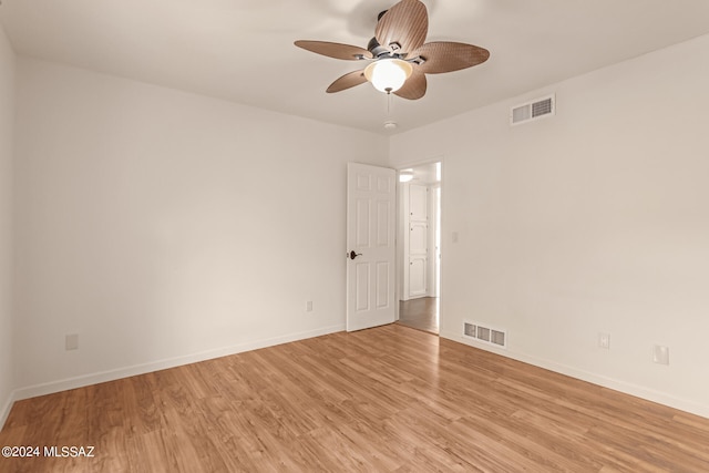 unfurnished room featuring light wood finished floors, baseboards, visible vents, and a ceiling fan