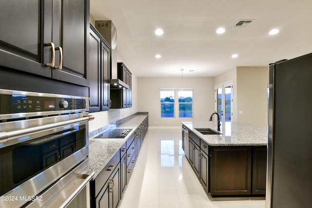 kitchen with pendant lighting, sink, light stone counters, and stainless steel appliances