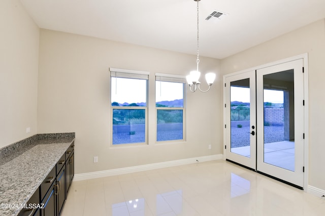 unfurnished dining area with french doors, light tile patterned floors, and a chandelier