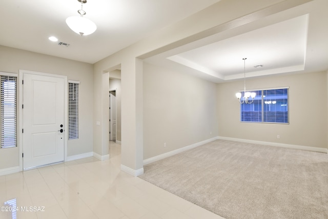 entryway featuring a chandelier, light carpet, and a raised ceiling