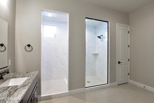 bathroom with tile patterned floors, a tile shower, vanity, and baseboards