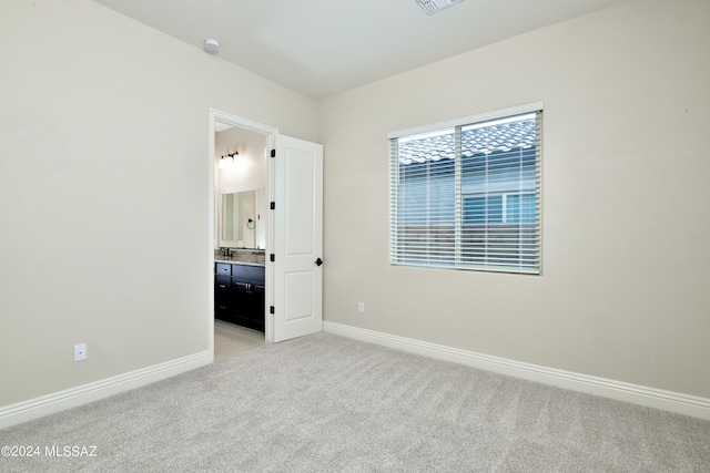 unfurnished bedroom featuring light carpet, visible vents, baseboards, and connected bathroom