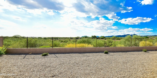 view of yard with fence, a mountain view, and a rural view