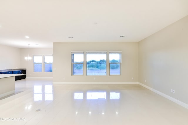 unfurnished room featuring light tile patterned floors, baseboards, visible vents, and a notable chandelier