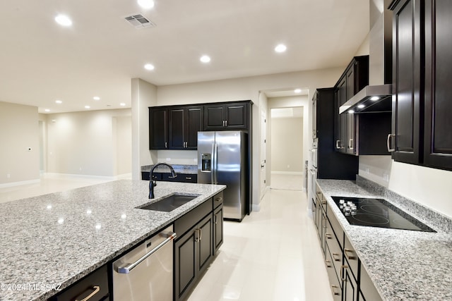 kitchen featuring wall chimney range hood, stainless steel appliances, sink, and light stone counters