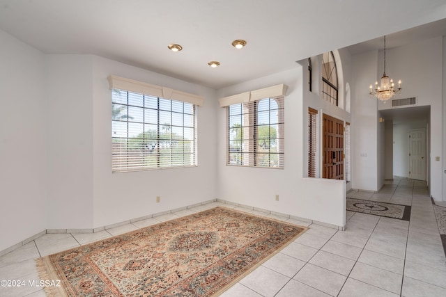 unfurnished room with an inviting chandelier, plenty of natural light, and light tile patterned floors