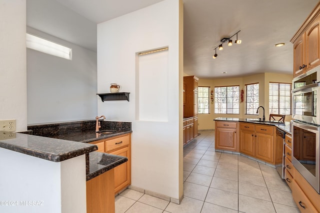 kitchen with dark stone counters, kitchen peninsula, appliances with stainless steel finishes, and sink