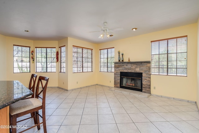 tiled living room with a fireplace and ceiling fan