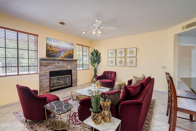 tiled living room with ceiling fan and a fireplace