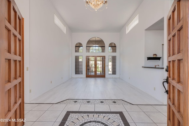 entryway featuring light tile patterned floors, a high ceiling, and a chandelier