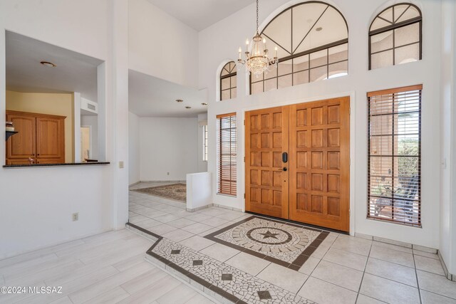 foyer with an inviting chandelier, a towering ceiling, and light hardwood / wood-style floors