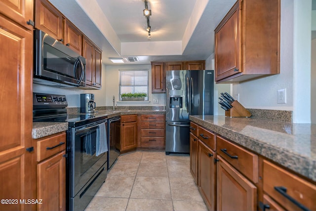 kitchen featuring black appliances, a raised ceiling, track lighting, and light tile patterned floors