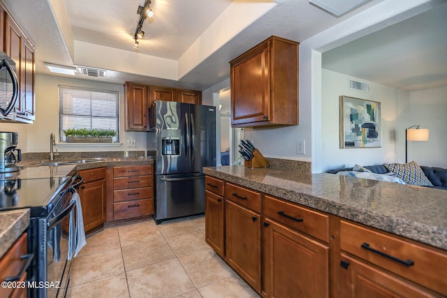 kitchen featuring a textured ceiling, light tile patterned flooring, sink, stainless steel appliances, and a raised ceiling