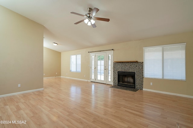 unfurnished living room with light hardwood / wood-style flooring, ceiling fan, a tile fireplace, and vaulted ceiling