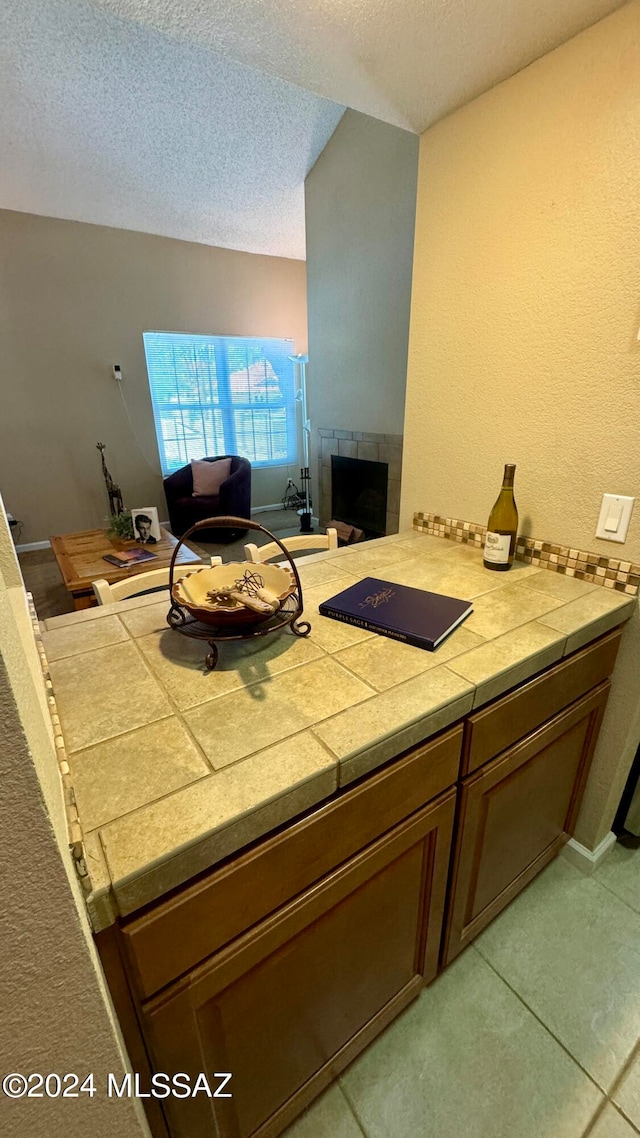 bathroom with a tiled fireplace, a textured ceiling, and tile patterned floors