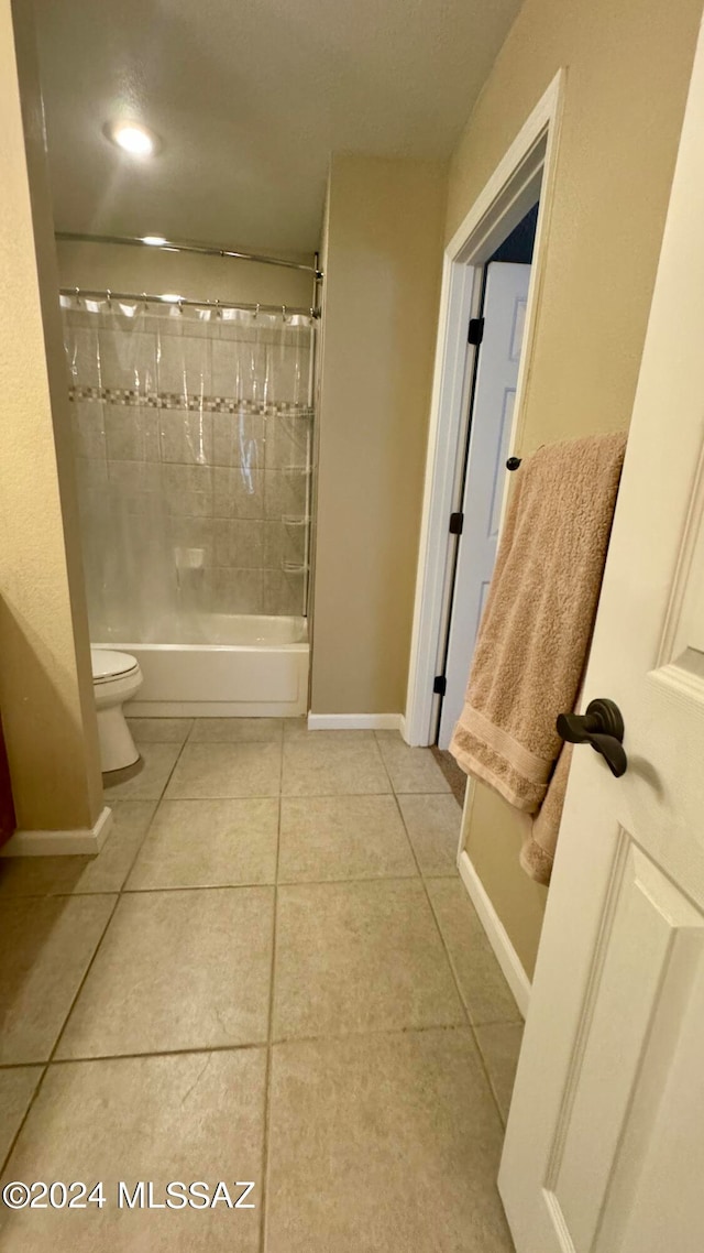 bathroom with tile patterned flooring, toilet, and tiled shower / bath combo