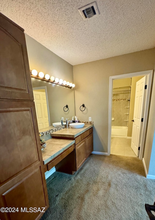 bathroom featuring a tile shower, a textured ceiling, and vanity