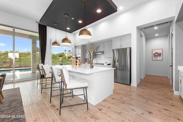 kitchen featuring gray cabinetry, a center island, decorative light fixtures, light wood-type flooring, and stainless steel fridge with ice dispenser