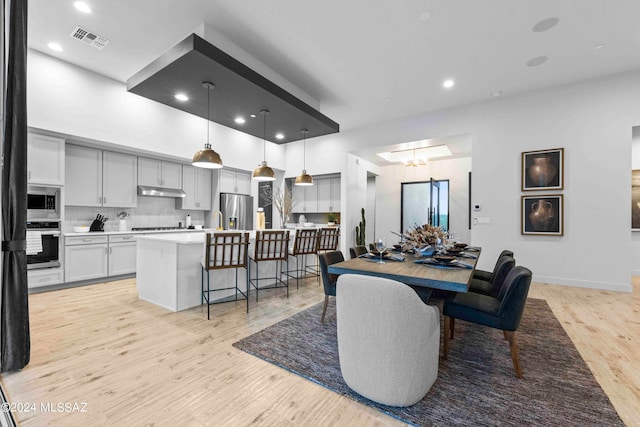 dining room with sink, an inviting chandelier, and light hardwood / wood-style flooring