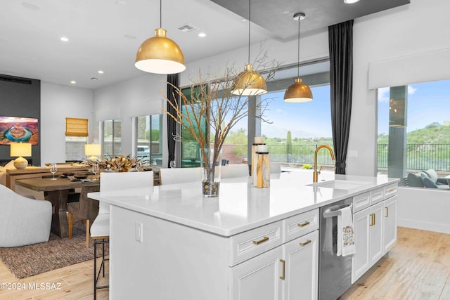 kitchen with light wood-type flooring, white cabinetry, sink, pendant lighting, and a kitchen island with sink