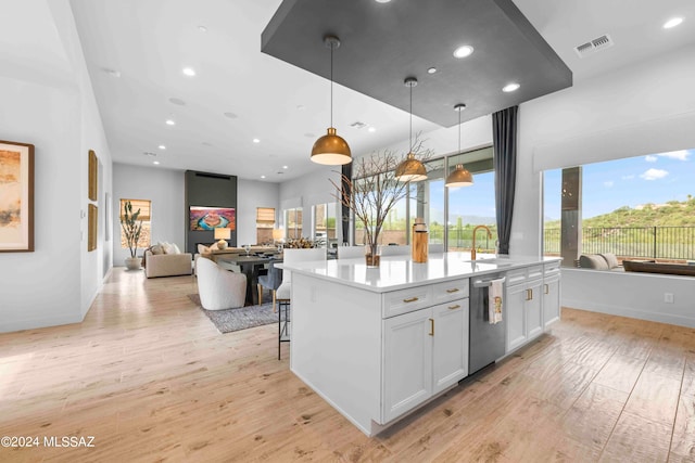 kitchen with an island with sink, plenty of natural light, white cabinets, and light hardwood / wood-style floors