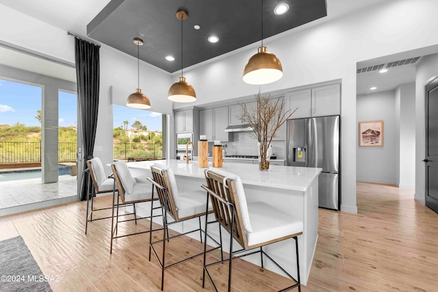 kitchen featuring light hardwood / wood-style flooring, gray cabinets, decorative light fixtures, and stainless steel refrigerator with ice dispenser