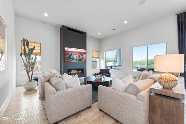 living room with a large fireplace and light wood-type flooring