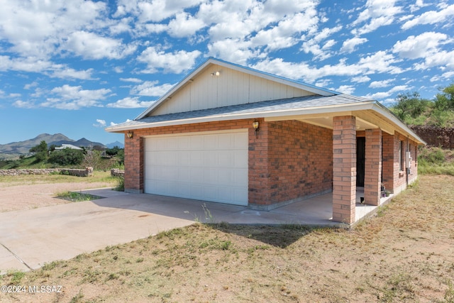 view of side of property with brick siding, a mountain view, and driveway