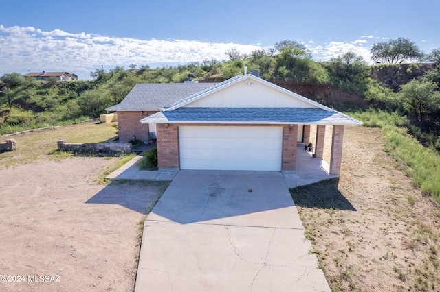 ranch-style home with a shingled roof, brick siding, driveway, and a garage