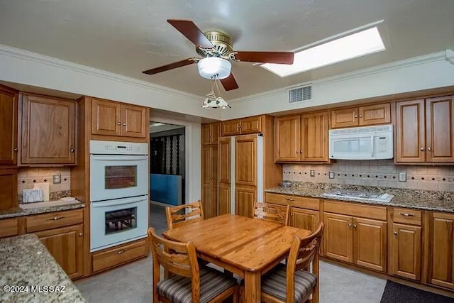 kitchen with white appliances, tasteful backsplash, light stone counters, and crown molding