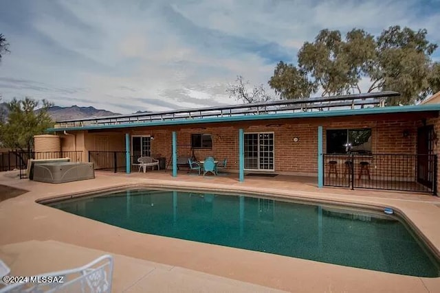 back of property featuring a swimming pool with hot tub and a patio area